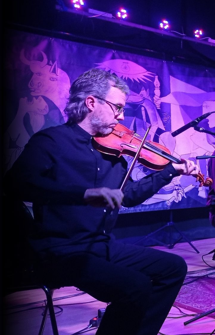 El Joan Sardans Pla tocant el violí en un concert amb il·luminació lila